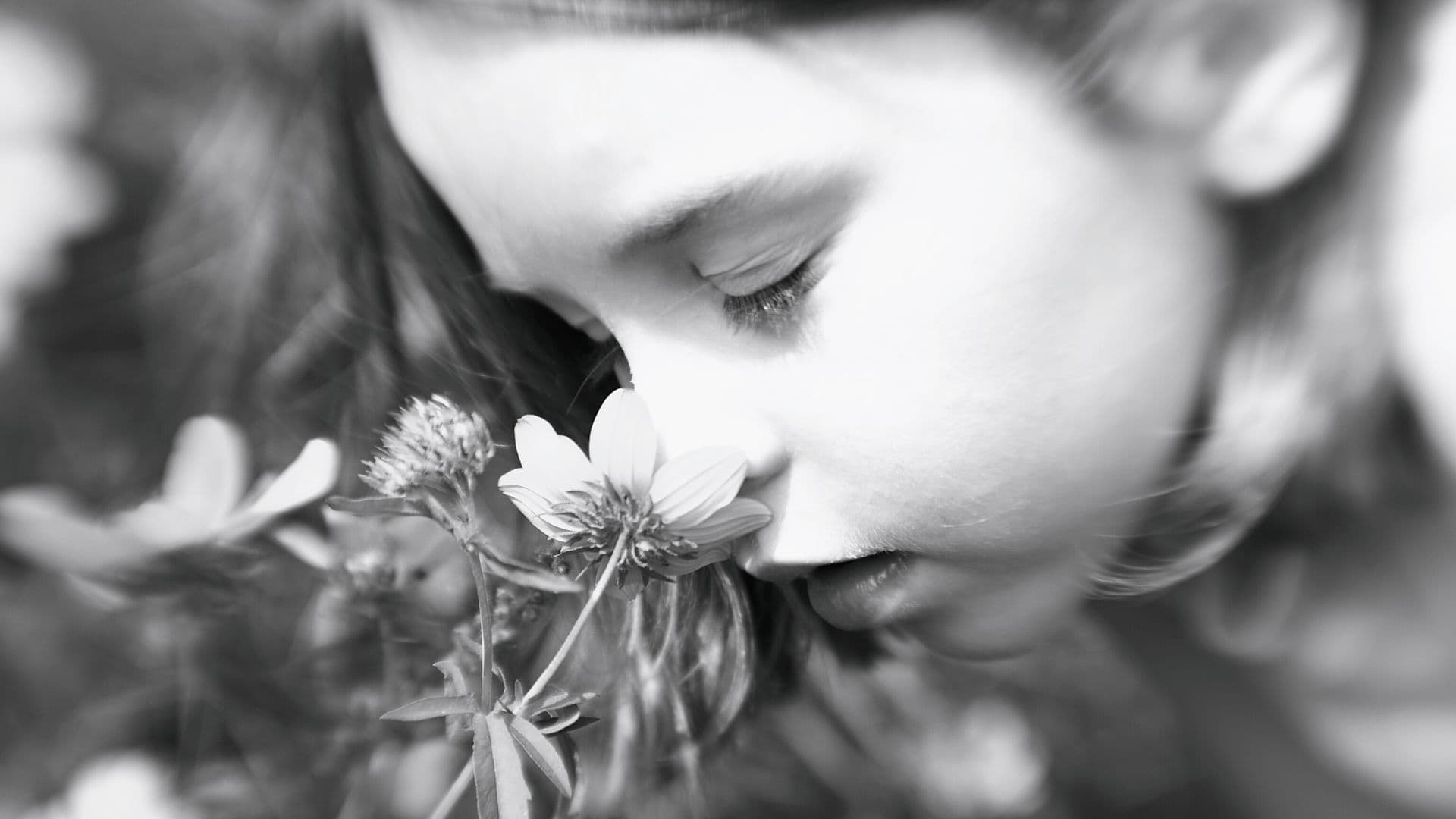 Gros plan en en noir et blanc d'une petite fille sentant une fleur